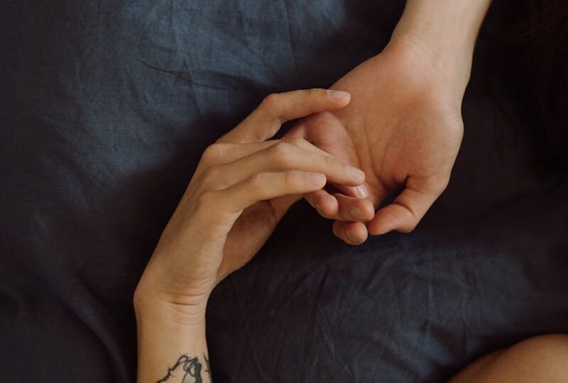 Two Persons Lying In Bed While Holding Hands