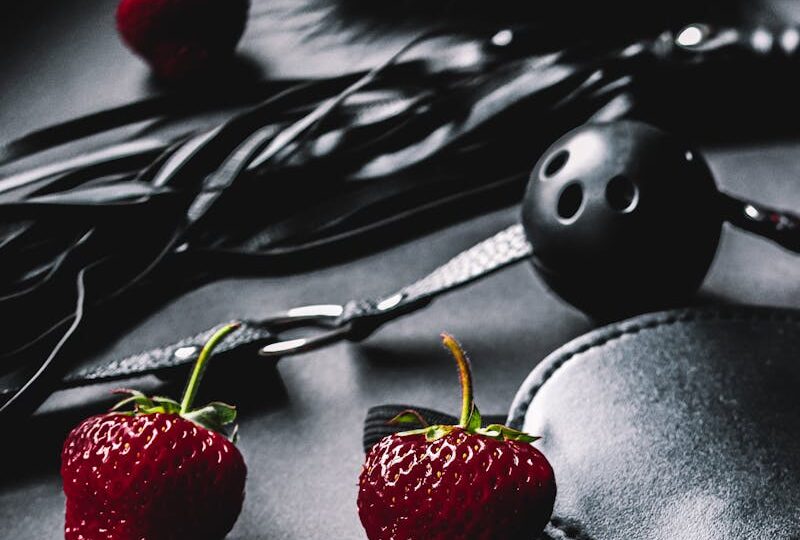 Strawberries Lying Next to Leather Erotic Toys